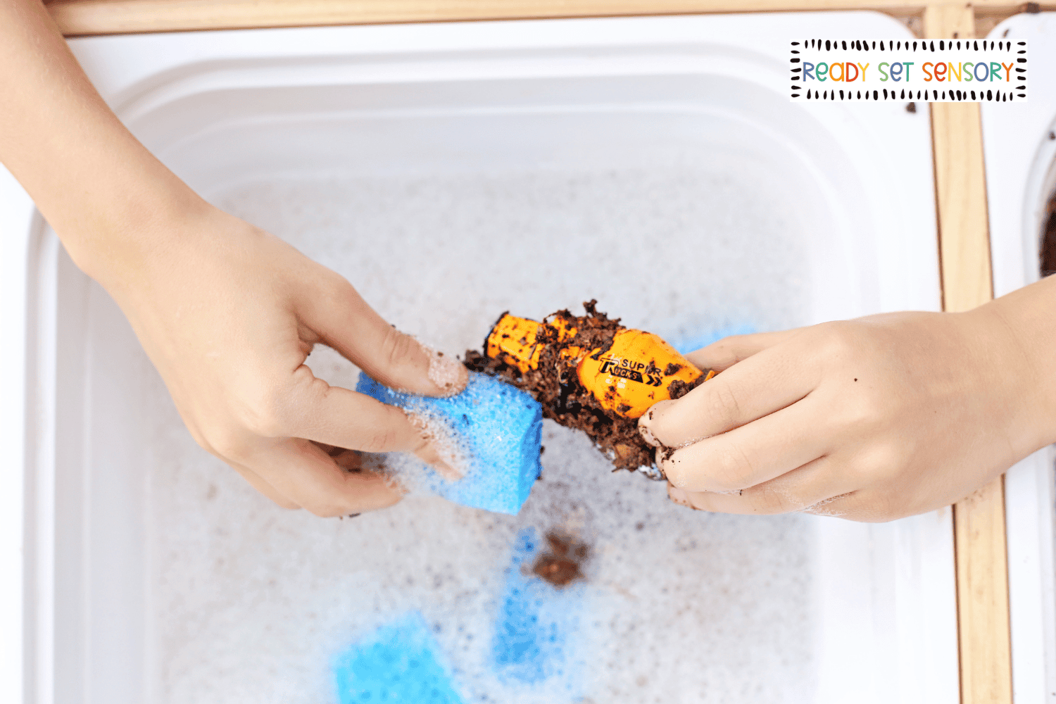 Washing toy truck with sponge in car wash sensory bin