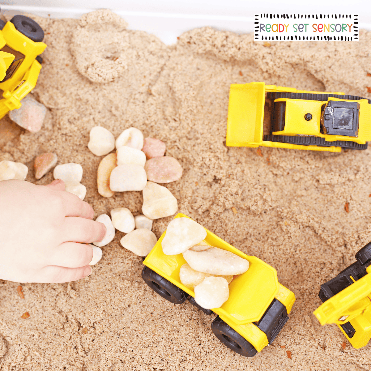 image.png Construction site sensory bin with toy trucks, sand, and rocks for sensory play