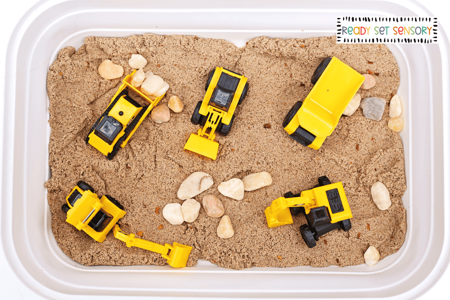 Construction site sensory bin with toy excavators and dump trucks in sand