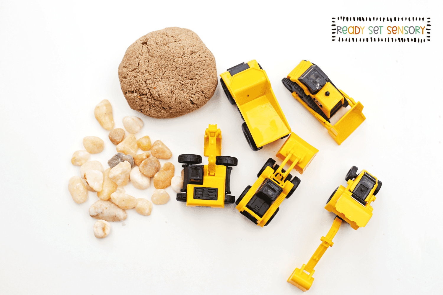 Construction site sensory bin supplies with toy trucks, sand, and stones
