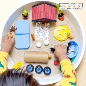 dog park sensory bin activity with toddler playing using toy dogs and sand