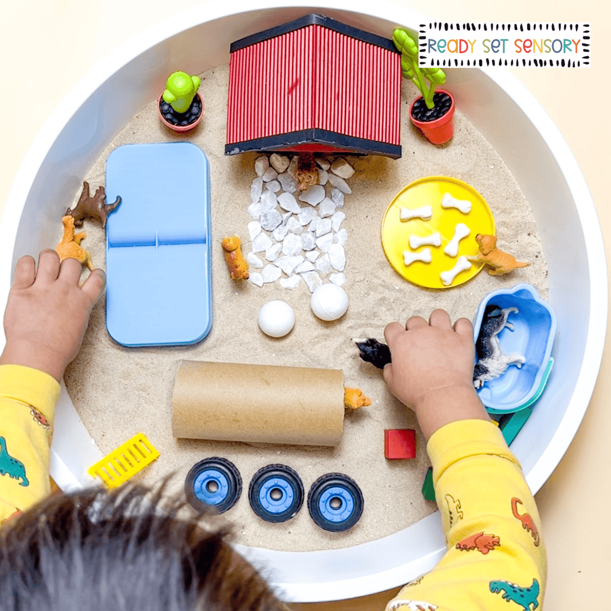 dog park sensory bin activity with toddler playing using toy dogs and sand