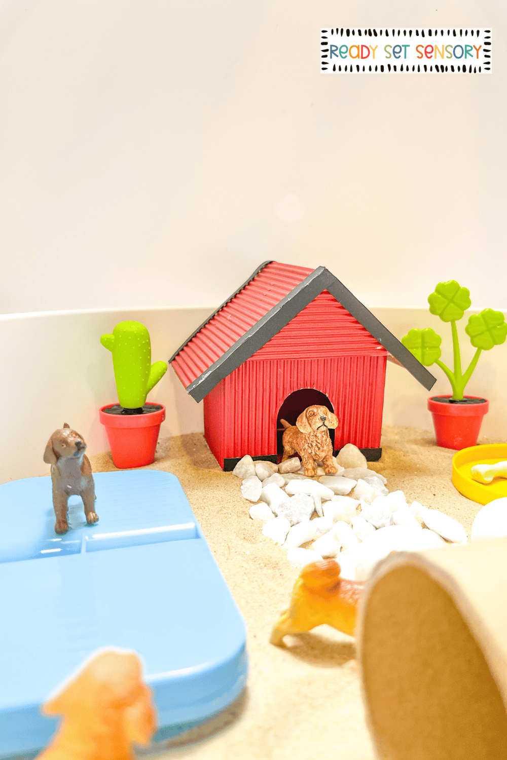 overhead view of dog park sensory bin with toy dogs and play accessories
