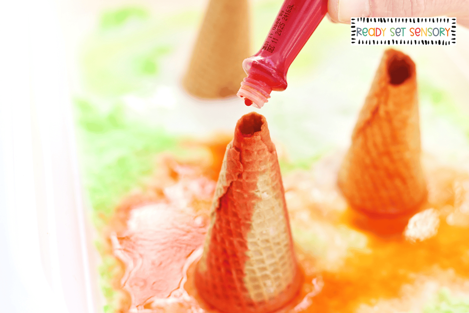 Adding colored liquid to fizzy volcano sensory bin