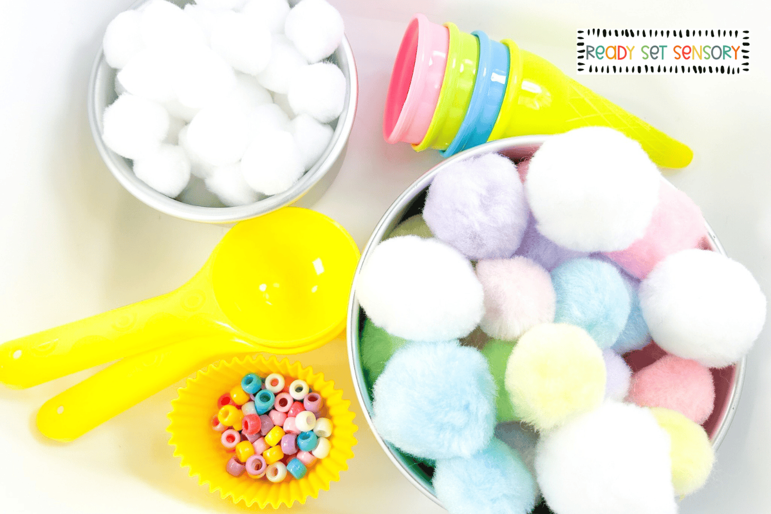 Ice cream sensory bin supplies including pom poms, scoops, cones, and beads