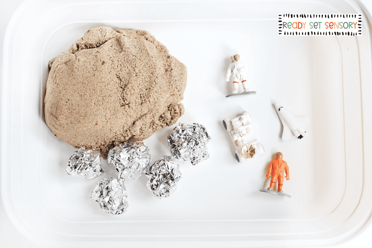 Moon landing sensory bin supplies including sand, astronauts, and space toys
