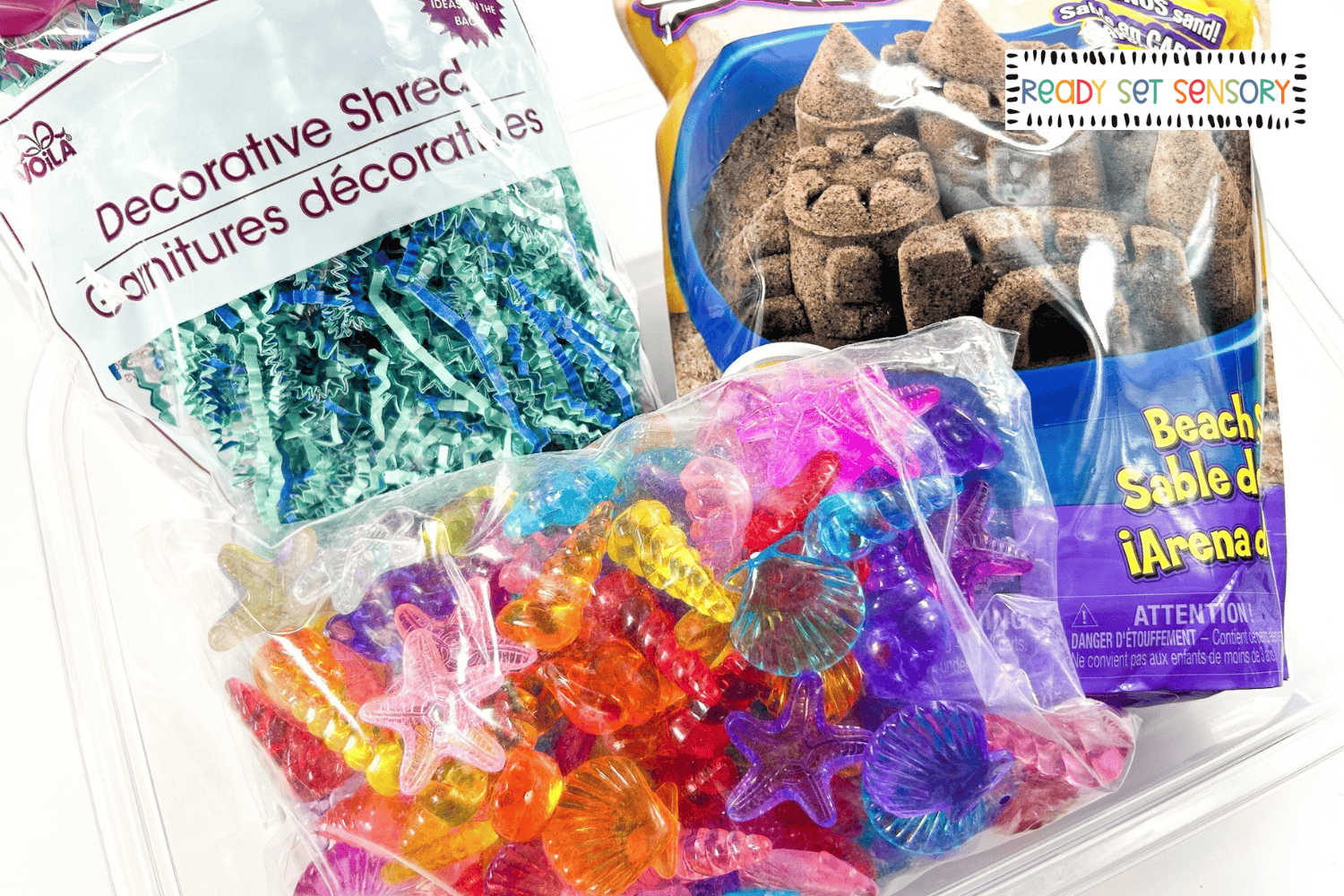 Seashell sensory bin supplies including kinetic sand, plastic seashells, and sensory filler