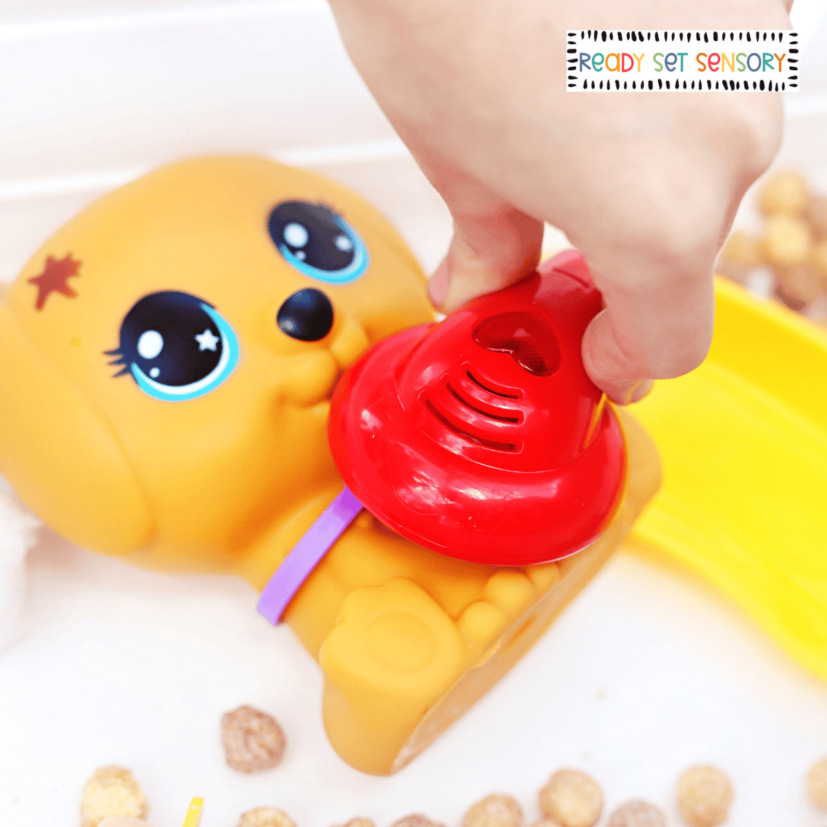 Toy vet clinic sensory bin with puppy figure, cereal base, and pretend medical tools