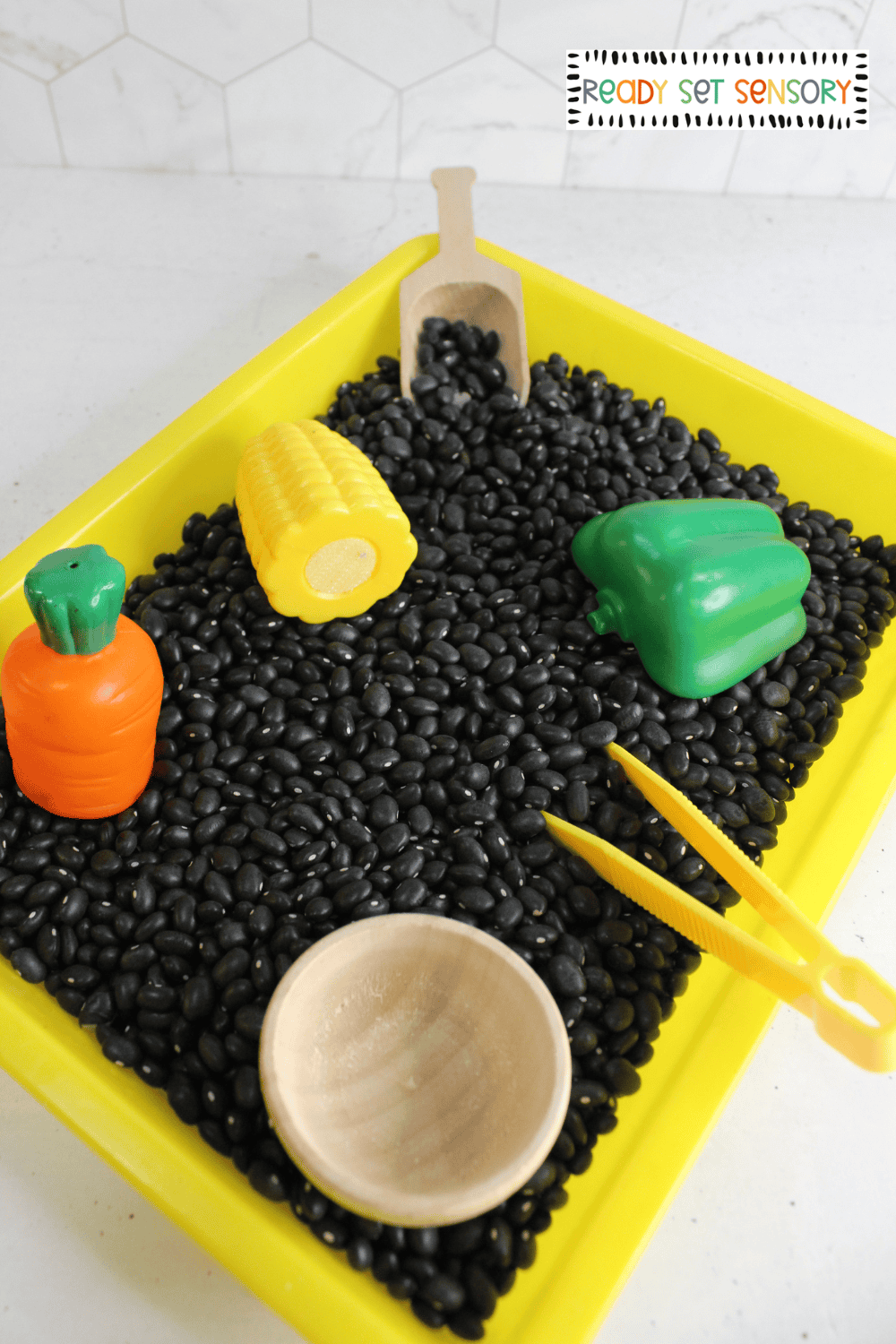 Fine motor veggie sensory bin with beans, scoops, and toy vegetables