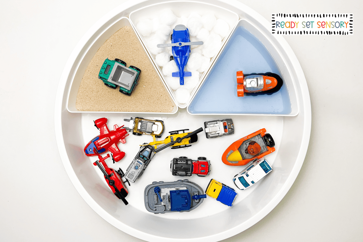 Vehicles sensory bin supplies with toy cars, trucks, planes, sand, and water