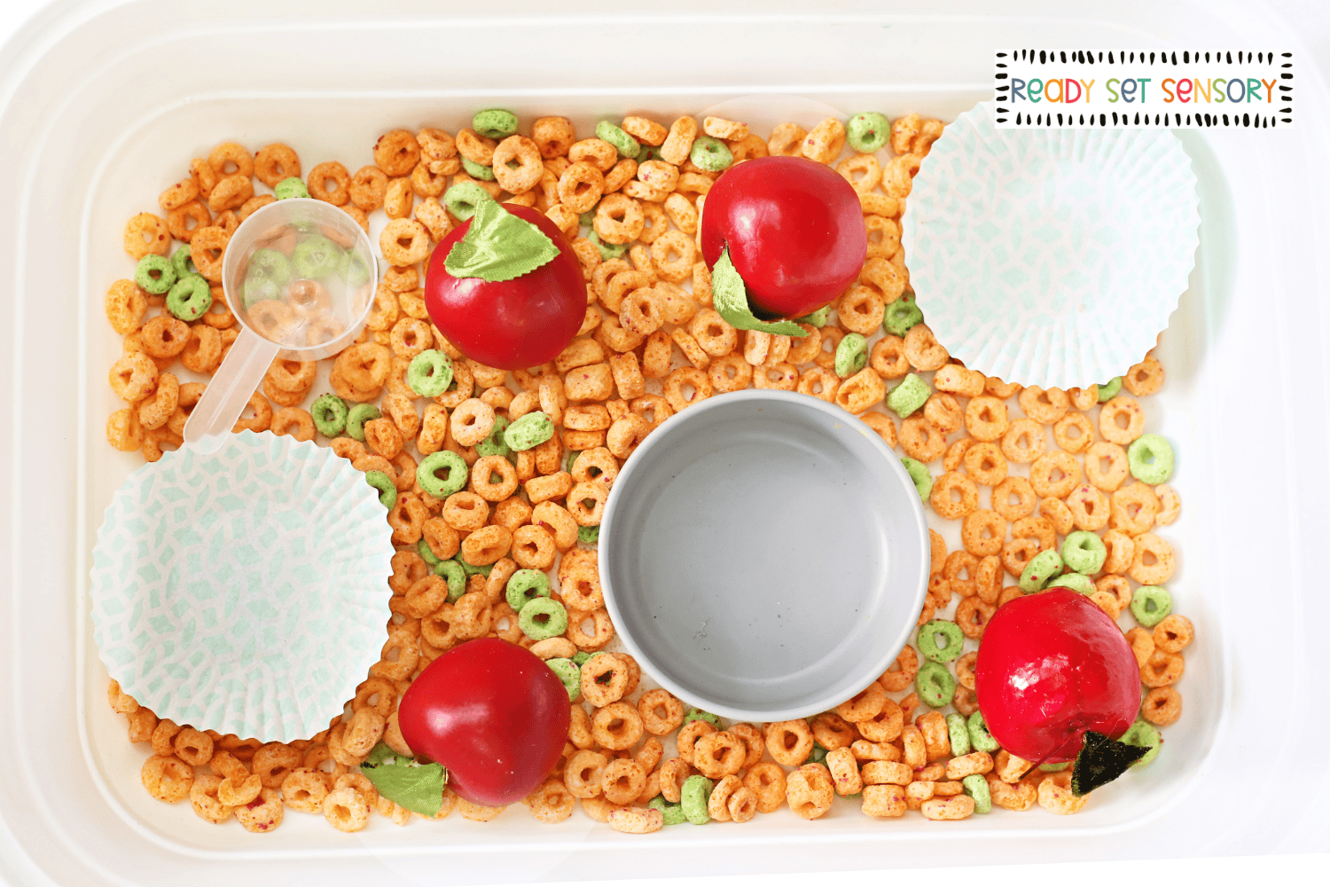 Apple Jacks sensory bin with scoop, apples, and sorting cups for preschool sensory play