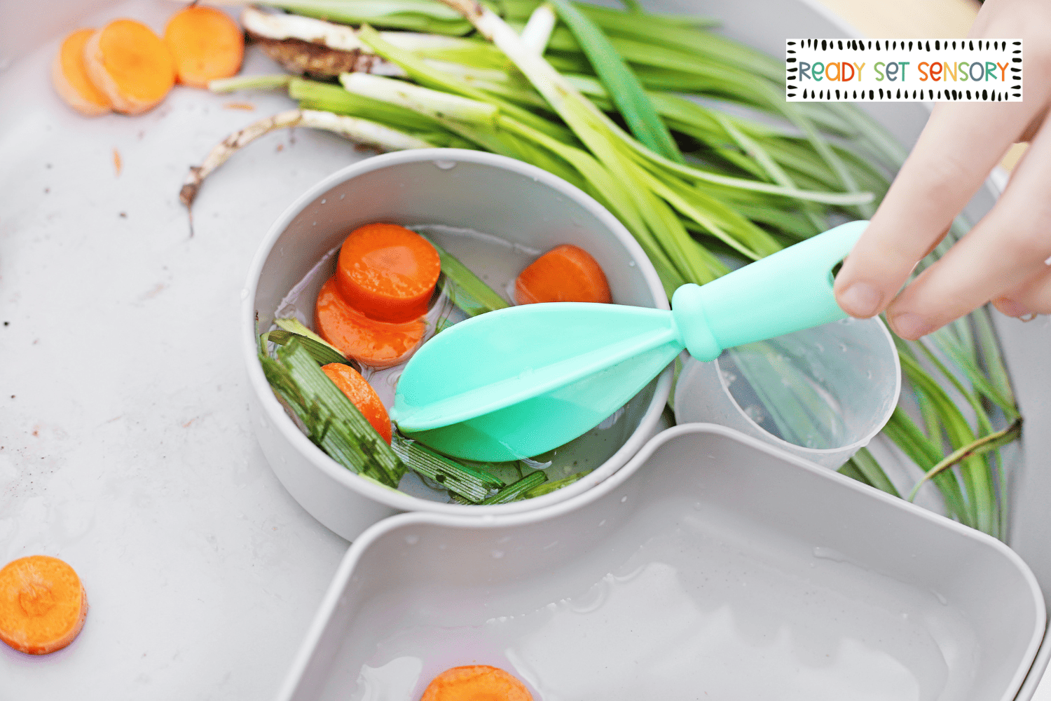 Close up of Bunny Bait sensory bin with carrots in water play tray