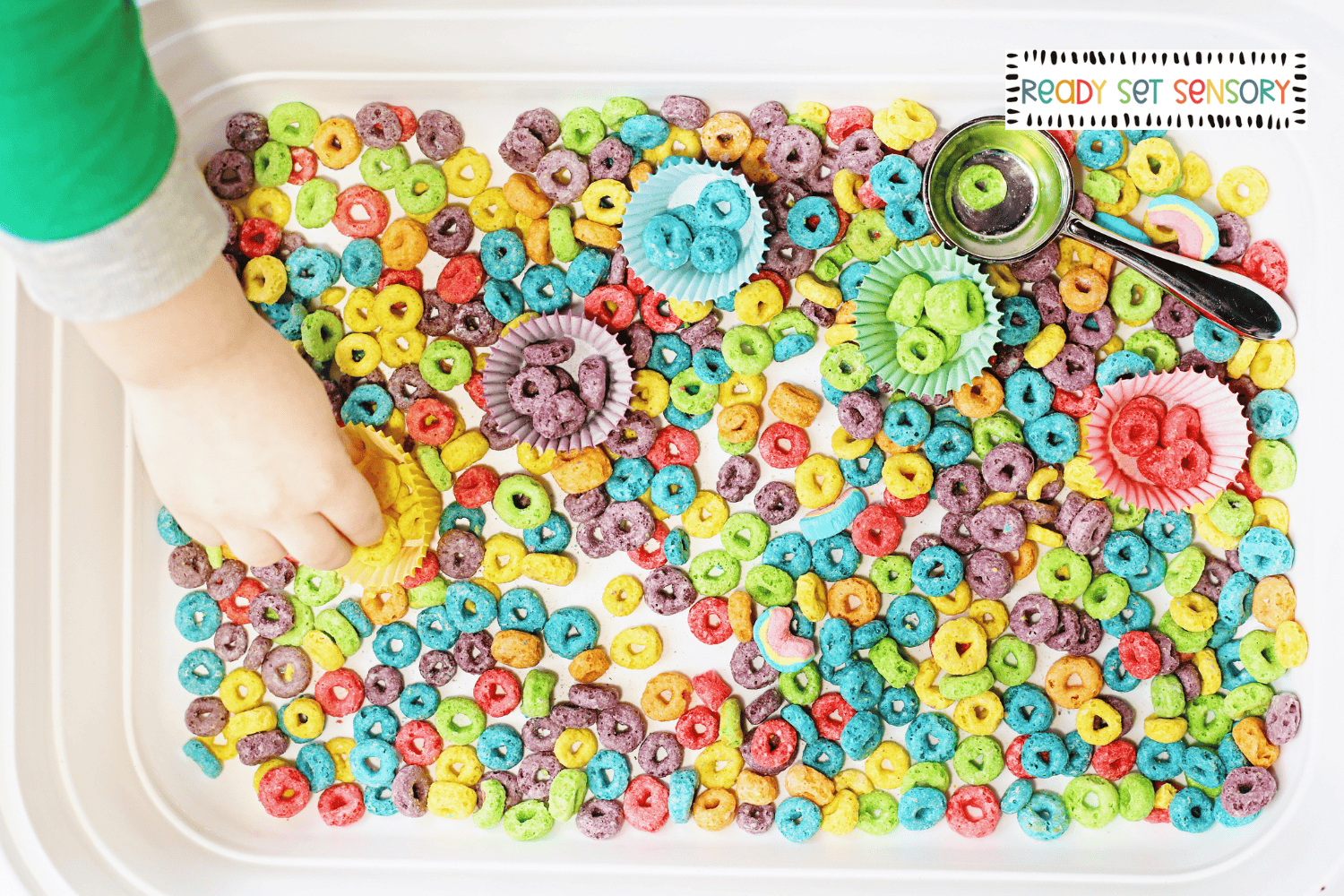 Toddler sorting cereal by color into cupcake liners sensory bin